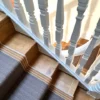 Yellow and brown flatweave stair runner installed on straight wooden stairs