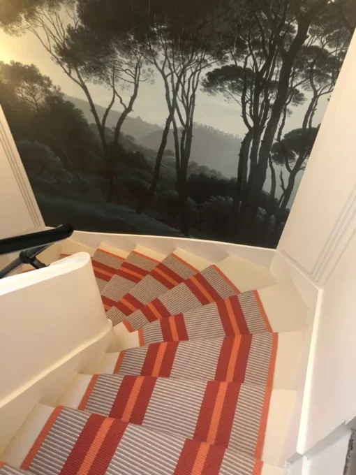 Tapis d'escalier tissé plat PNT29 Tangerine, 100% laine.ngbone flatweave stair runner with black stair rods installed on black wooden staircase.