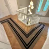 Black and beige striped flatweave stair runner installed on wooden landing