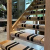 Black and beige flatweave stair runner installed on wooden open tread staircase