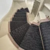 Black flatweave stair runner with brown woven border on grey winding staircase with brass stair rods