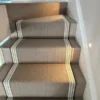 Beige flatweave stair runner with white and grey woven border installed on straight stairs