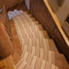 Beige flatweave stair runner with white and red stripes on wooden winding staircase