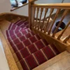 Tapis d’escalier tissé plat à rayures rouges, installé sur un escalier en bois.