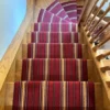 Tapis d’escalier tissé plat à rayures rouges, installé sur un escalier en bois.