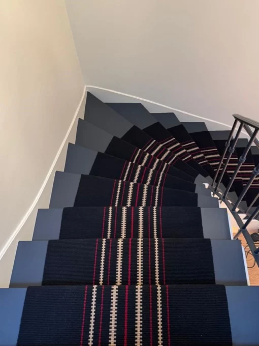 Black flatweave custom stair runner with central beige and red zip stripes on blue stairs