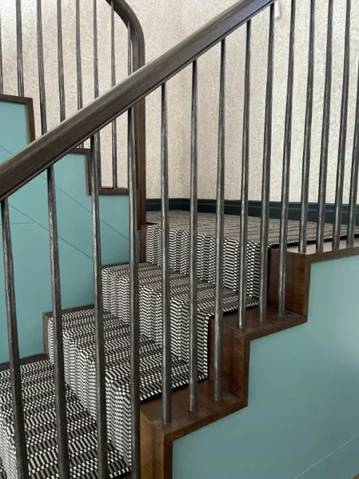 Black, white and grey striped stair runner installed on wooden stairs and landing