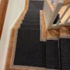 Black flatweave stair runner with striped woven border installed on straight steps and in mitred form on two quarter landings