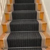 Black flatweave stair runner with stair rods installed on a straight wooden staircase