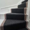 Black stair runner with Taupe woven border installed on white winding staircase