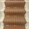 Cinnamon-coloured stair runner with green triangle pattern on white wooden stairs