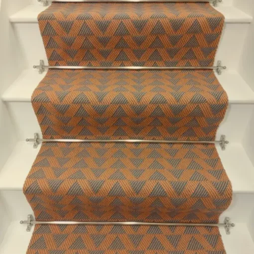 Cinnamon-coloured stair runner with green triangle pattern on white wooden stairs