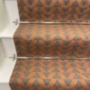 Cinnamon-coloured stair runner with green triangle pattern on white wooden stairs