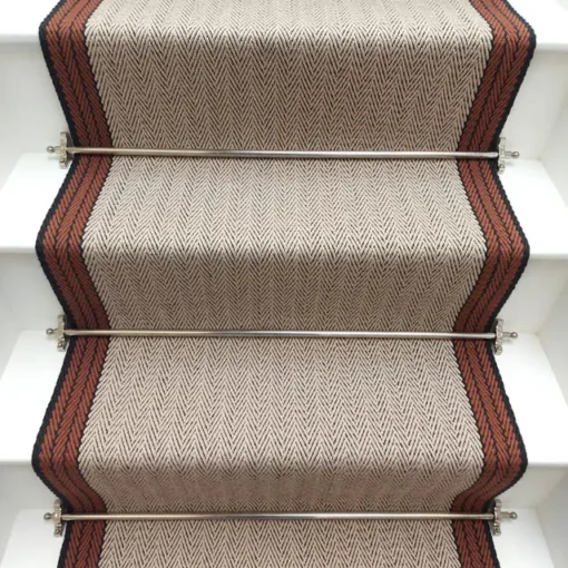 Tapis d’escalier plat ivoire avec bordure tissée orange et grise sur des marches blanches.
