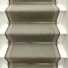 Tapis d’escalier plat vert avec bordure tissée blanche et grise sur des marches blanches.