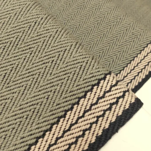 Tapis d’escalier plat vert avec bordure tissée blanche et grise sur des marches blanches.